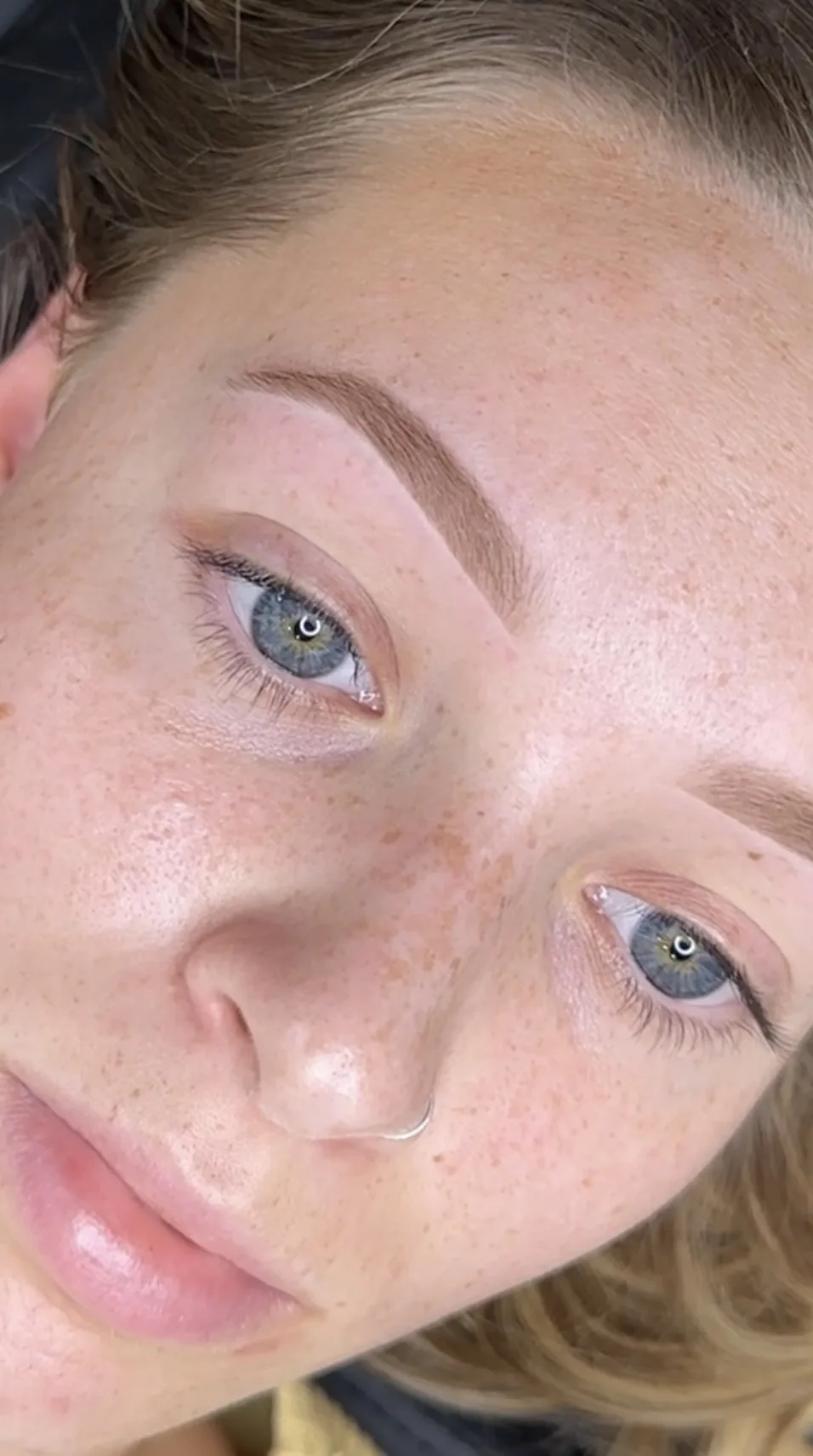 Freckled client with laminated brushed-up brows in natural daylight